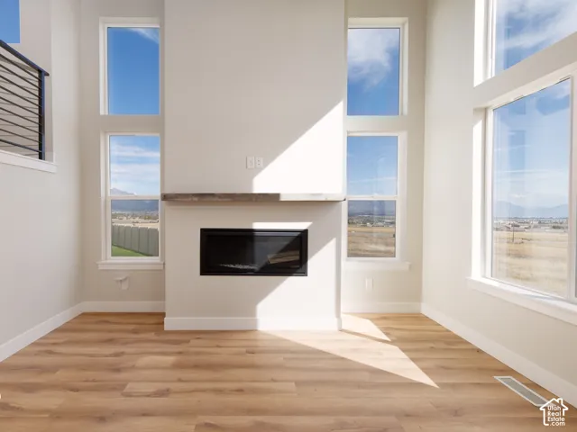 Hardwood-style flooring, a built-in fireplace with a wood-finish mantle, and multiple tall windows