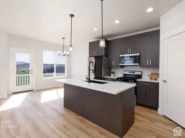 Modern kitchen featuring dark wood-finish cabinetry, stainless steel appliances, a center island with a white countertop, and wood-finish flooring