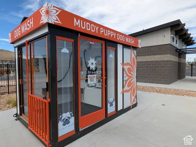 Dedicated dog wash station featuring glass doors, a vibrant orange and black exterior, and a concrete pad