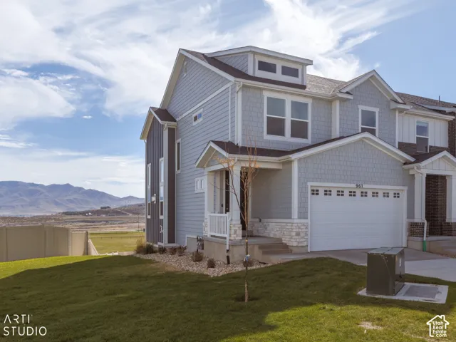 Two-story residence featuring light gray siding with shingle accents and white stone detailing