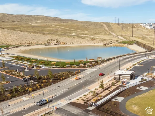 Recreational lake with sandy shoreline, paved walking paths, open green space, picnic areas, volleyball courts and designated parking areas