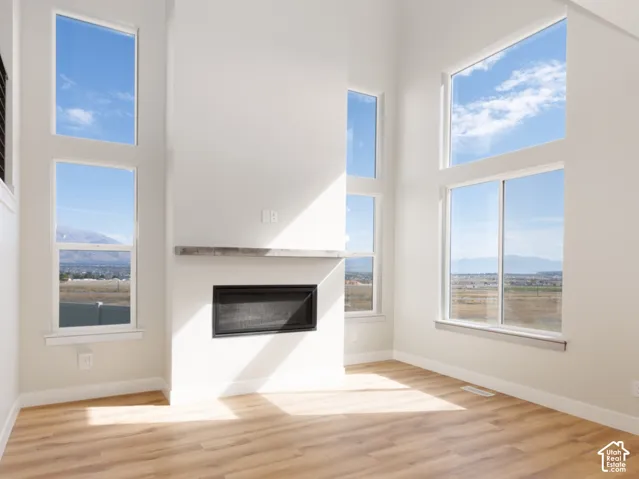 Vaulted ceiling, wood-finish flooring, white walls, built-in fireplace, and expansive windows