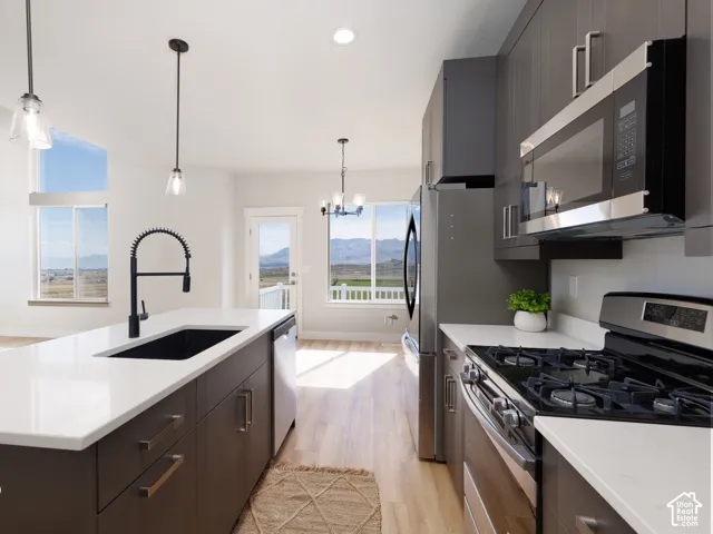 Modern kitchen featuring a large island with white countertops, dark wood-finish cabinetry, stainless steel appliances, and a black gooseneck faucet