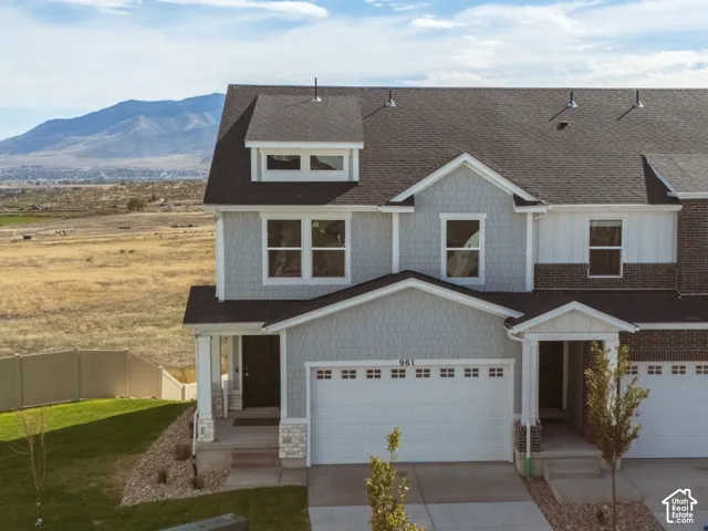Contemporary townhome exterior featuring an attached two-car garage, partial stone facade, and a paved driveway