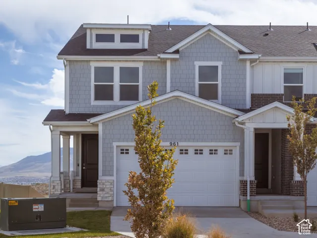 Attached two-car garage, dormer window, covered entry, and light-colored siding