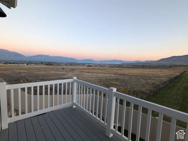 Second-story balcony with composite decking and white railing, overlooking a vast landscape with distant mountains