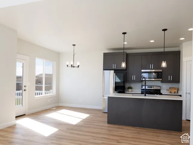 Wood-finish flooring, white walls, and a contemporary kitchen with dark cabinetry