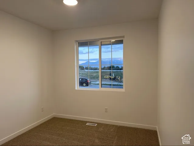 Neutral-toned interior room with wall-to-wall carpeting and a multi-pane sliding window featuring mountain scenery