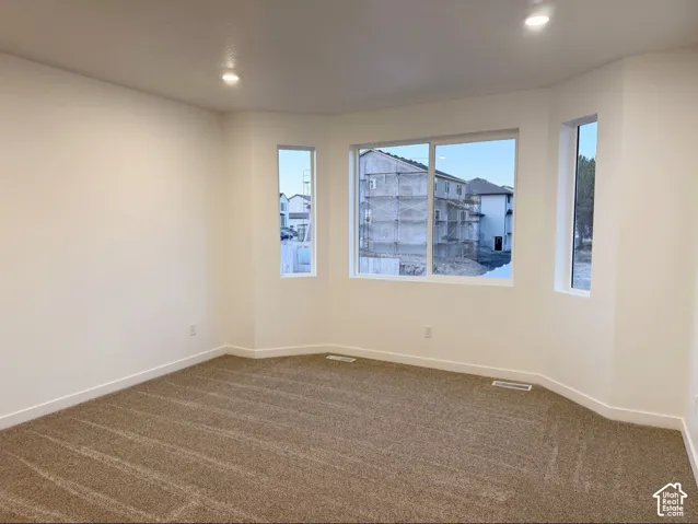 Neutral-toned carpeting, recessed ceiling lighting, and a bay window configuration featuring multiple panes