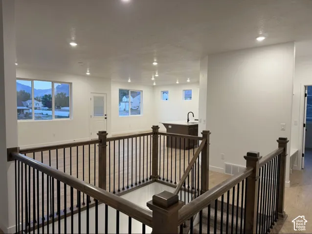 Interior featuring wood-finish flooring, recessed lighting, and a staircase with a wood railing and black metal balusters
