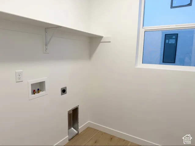 Utility room featuring wood-finish flooring, white walls, a built-in wall shelf, and a window