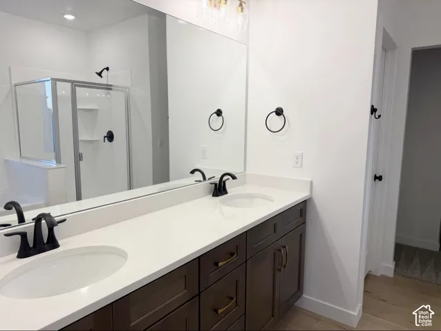 Double vanity featuring dark cabinetry, solid-surface countertops with dual undermount sinks, matte black widespread faucets, and a full-width mirror
