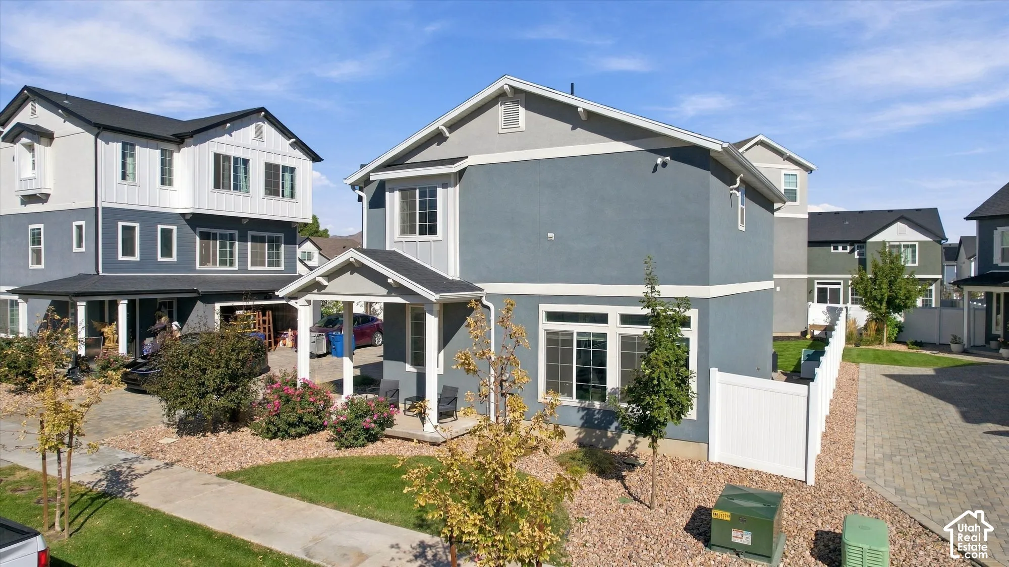 Contemporary exterior featuring a covered porch entry, multiple windows, and a paved driveway