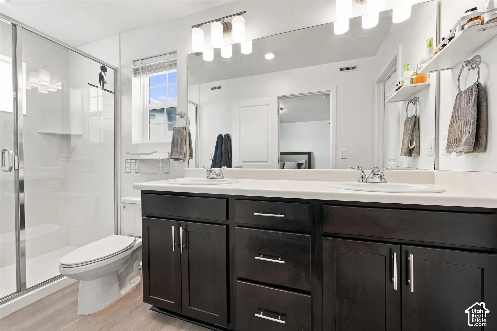 Dual vanity with dark wood-finish cabinetry, chrome hardware, and white countertops