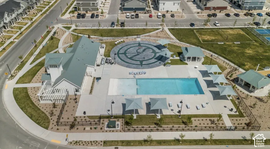 Community clubhouse with an outdoor swimming pool, surrounded by paved lounge areas, covered pergolas, and landscaped grounds