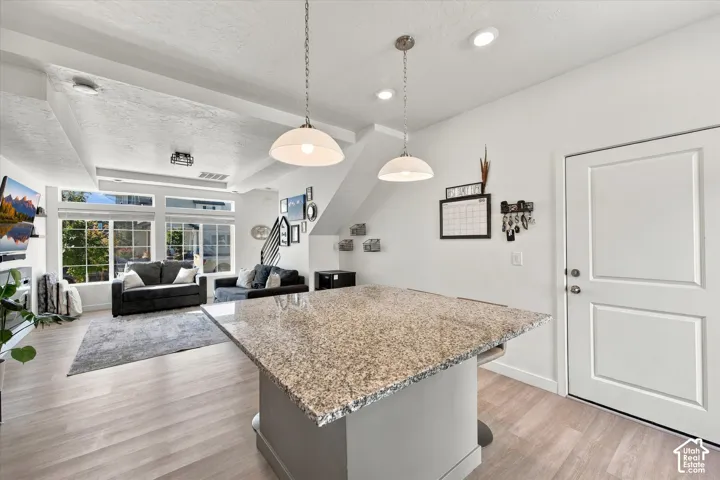 Kitchen island with a granite-style countertop, wood-finish flooring, recessed lighting, and a white paneled door