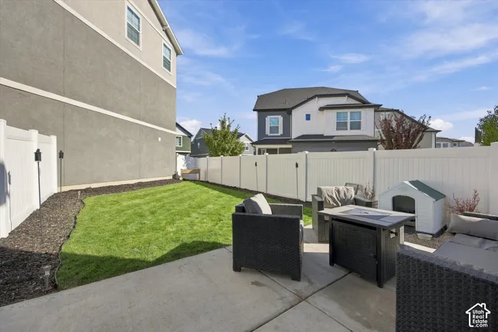 Private backyard featuring a concrete patio, manicured lawn, and white privacy fencing