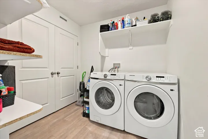 Laundry area featuring wood-finish flooring, built-in shelving, white walls, and bi-fold doors