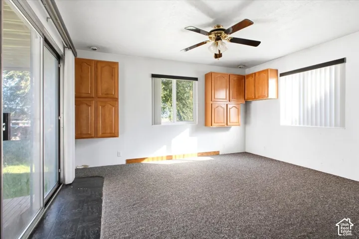 Recessed lighting, ceiling fan with integrated light fixture, light wood-finish cabinetry, sliding glass door, and fixed pane window