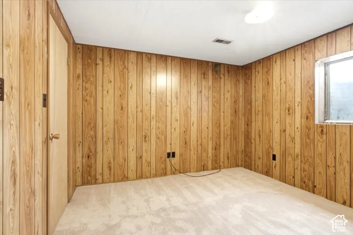 Carpeted flooring, paneled walls, ceiling-mounted light fixture, and a window for natural light