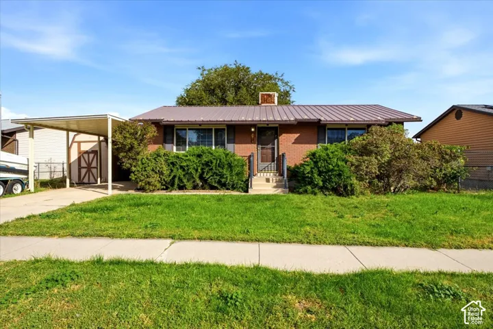Brick exterior with a metal roof, featuring a covered carport and a paved driveway