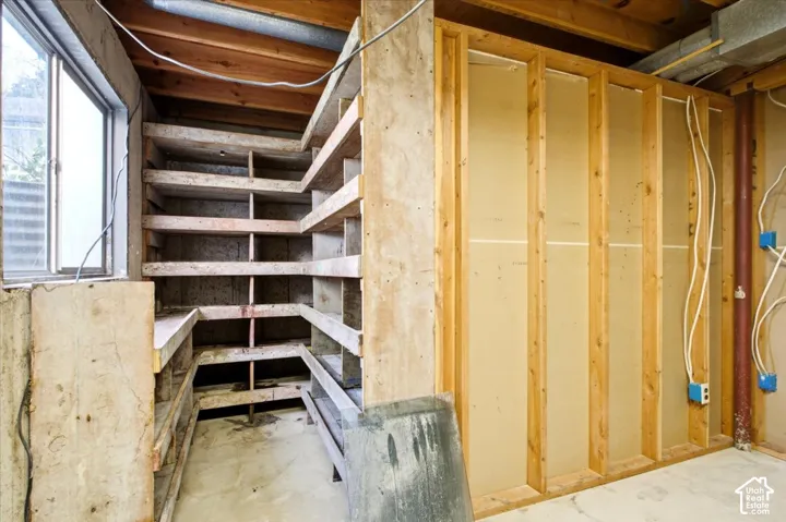 Built-in wooden shelving, exposed wood ceiling, concrete flooring, and an exterior window