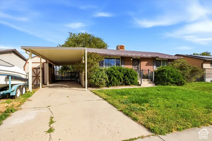 Brick exterior with a metal roof, front yard, and covered carport