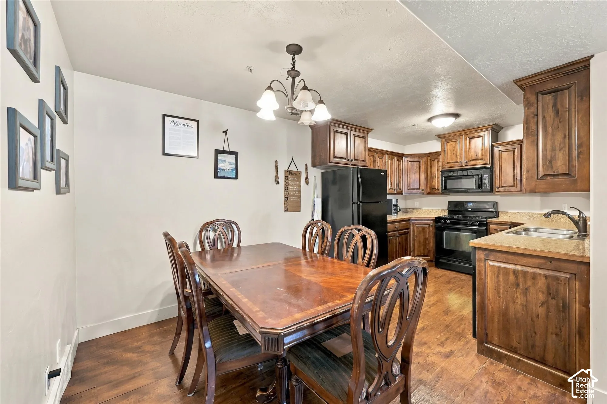 Kitchen featuring wood-finish flooring, wood cabinetry, stone-finish countertops, and black appliances