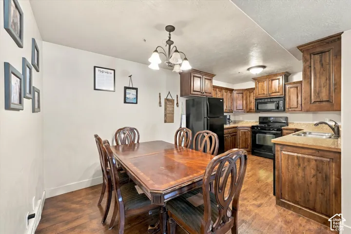 Kitchen featuring wood-finish flooring, wood cabinetry, stone-finish countertops, and black appliances