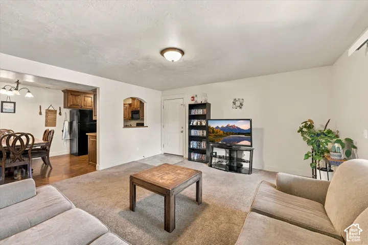 Archway pass-through to the kitchen, dining area with wood-finish flooring, recessed lighting, and wall-mounted light fixture
