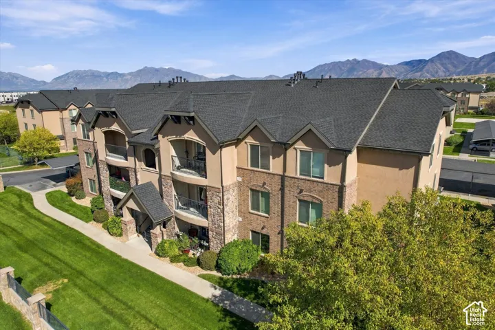 Multi-story building featuring balconies, stone veneer accents, and a dark shingle roof