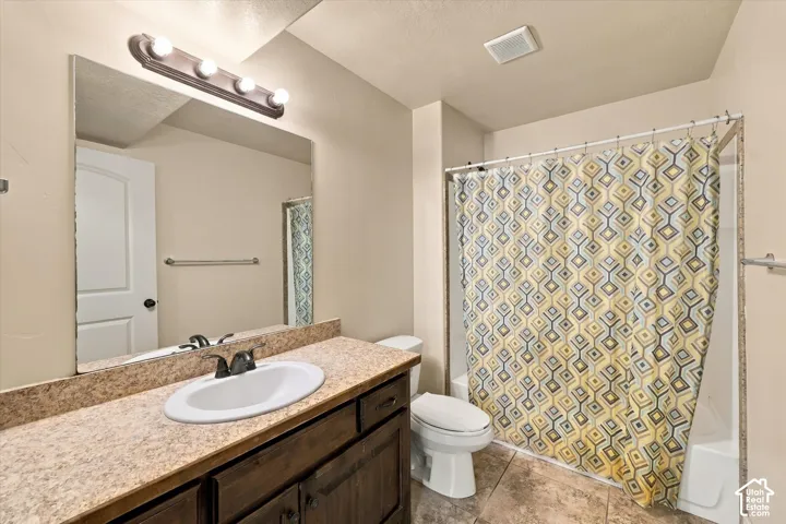 Vanity with an integrated sink and bronze-finish faucet, an overhead four-bulb vanity light, full-width mirror, and a shower-over-tub combination