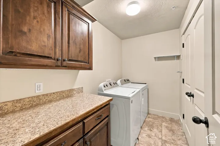 Wood-finish cabinetry with dark hardware, speckled countertop, and tiled flooring