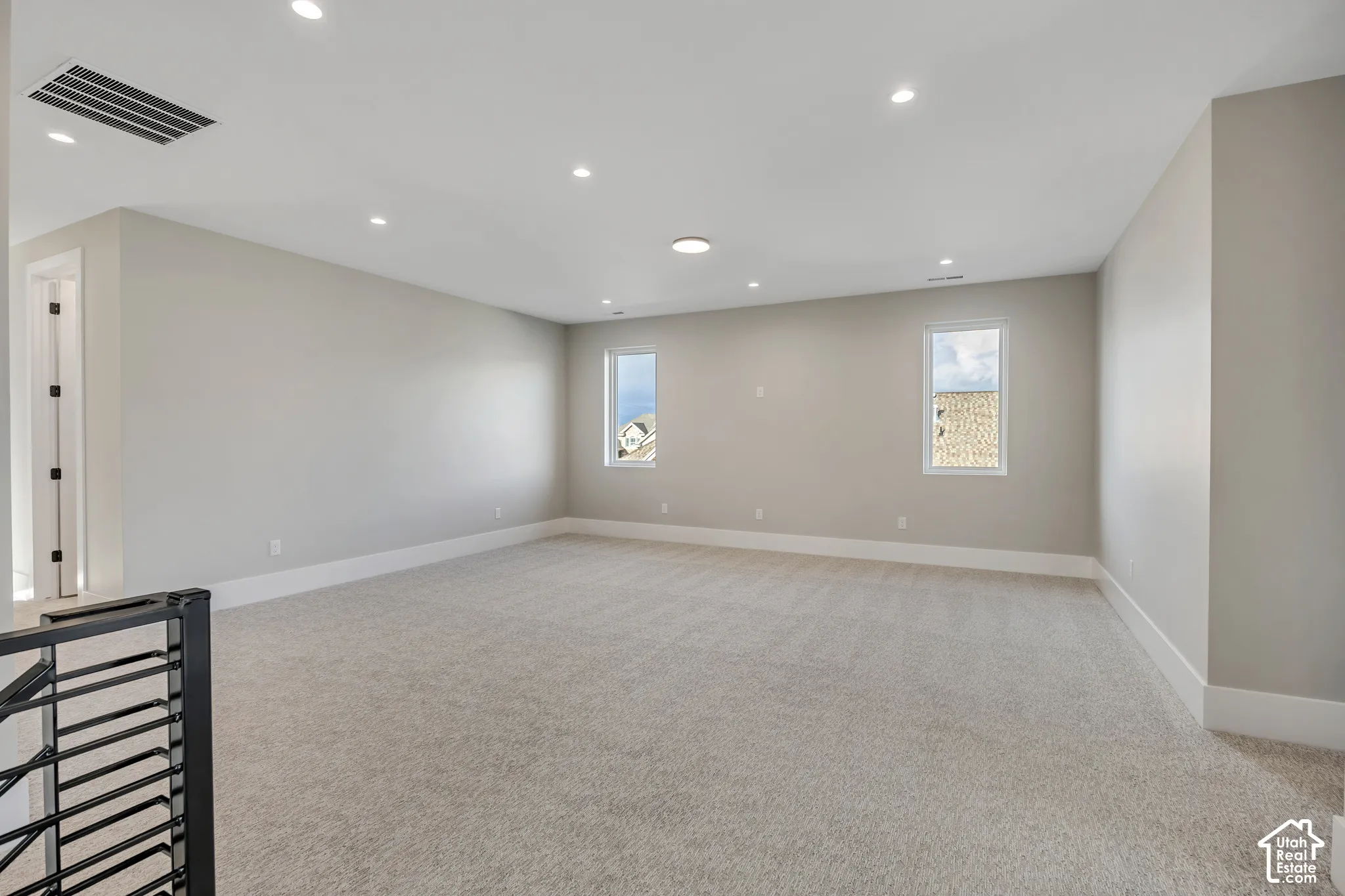 Spacious room with light neutral carpet flooring, recessed ceiling lighting, and multiple windows