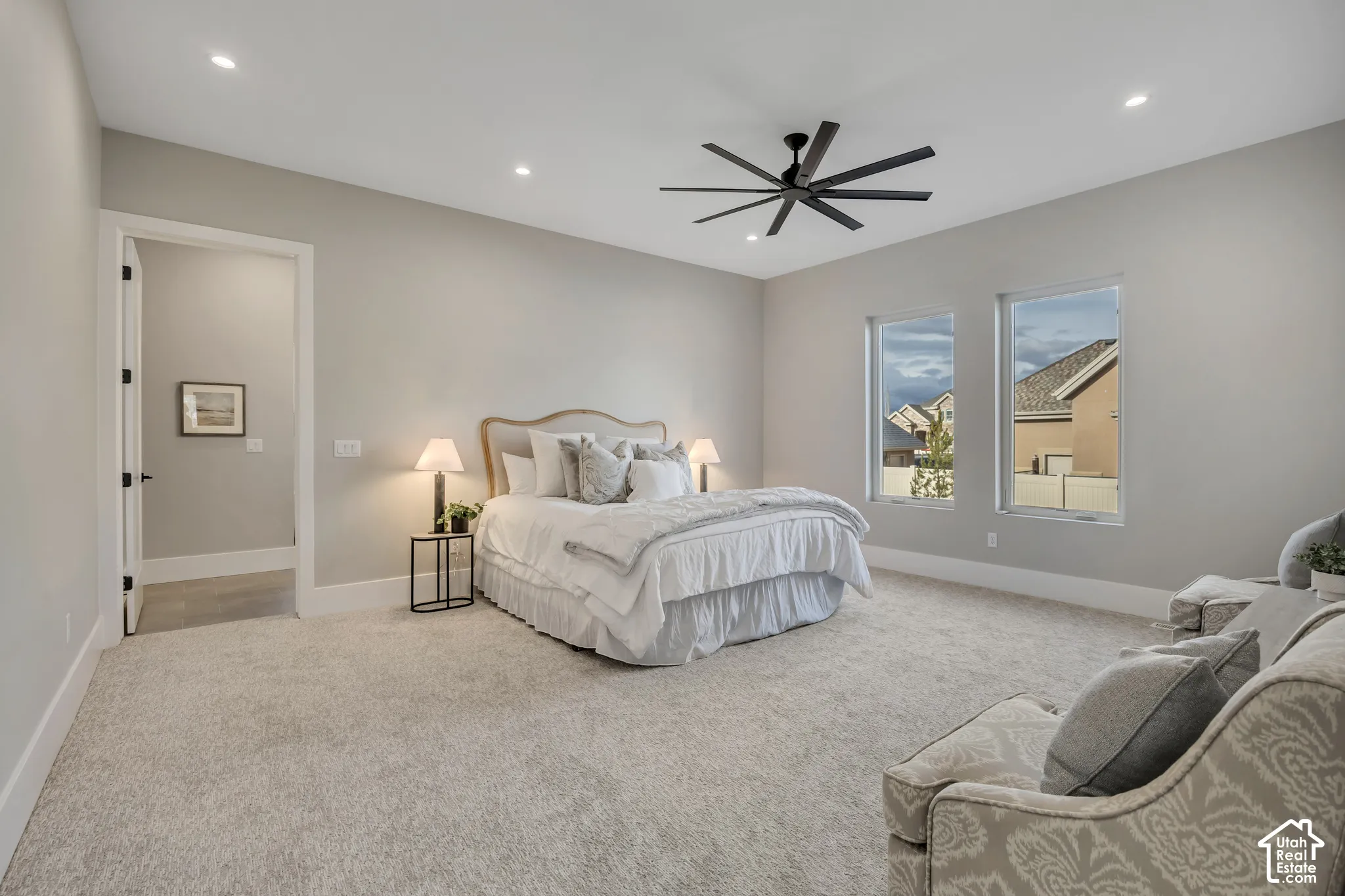 Recessed lighting, a modern ceiling fan, two windows, and light gray wall finishes
