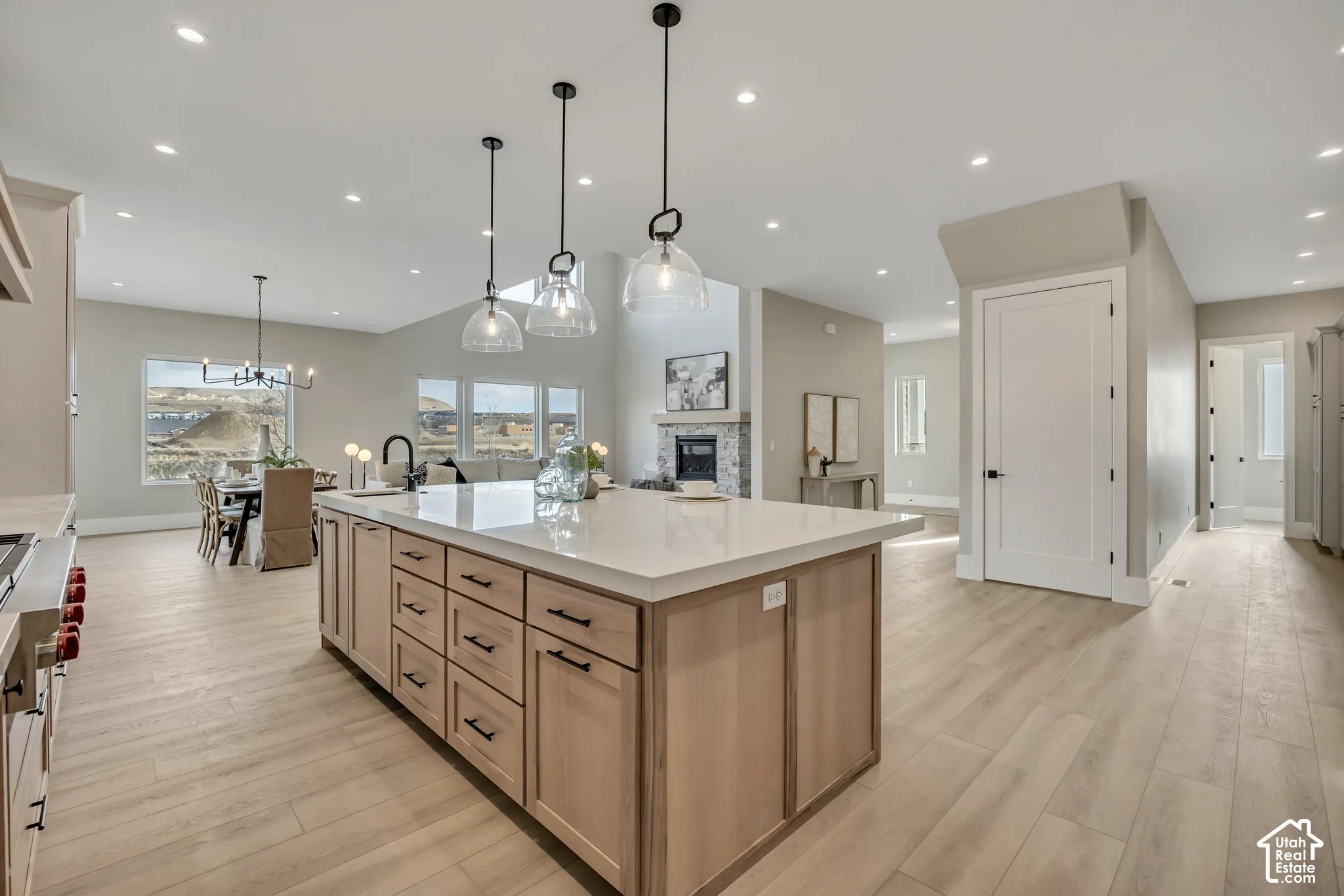 Open-concept living space featuring a large kitchen island with light wood cabinetry, recessed lighting, and wood-finish flooring