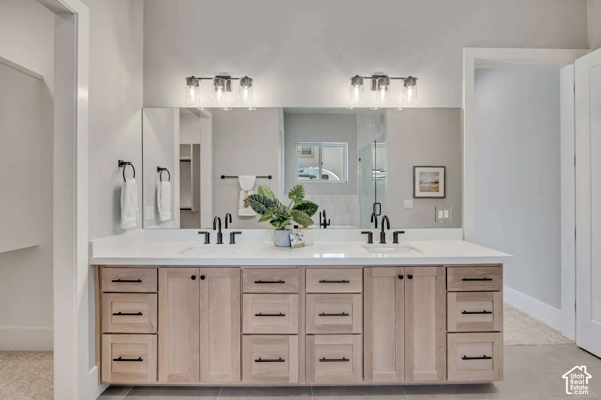 Dual-sink vanity with wood-finish cabinetry, white quartz countertop, and matte black hardware