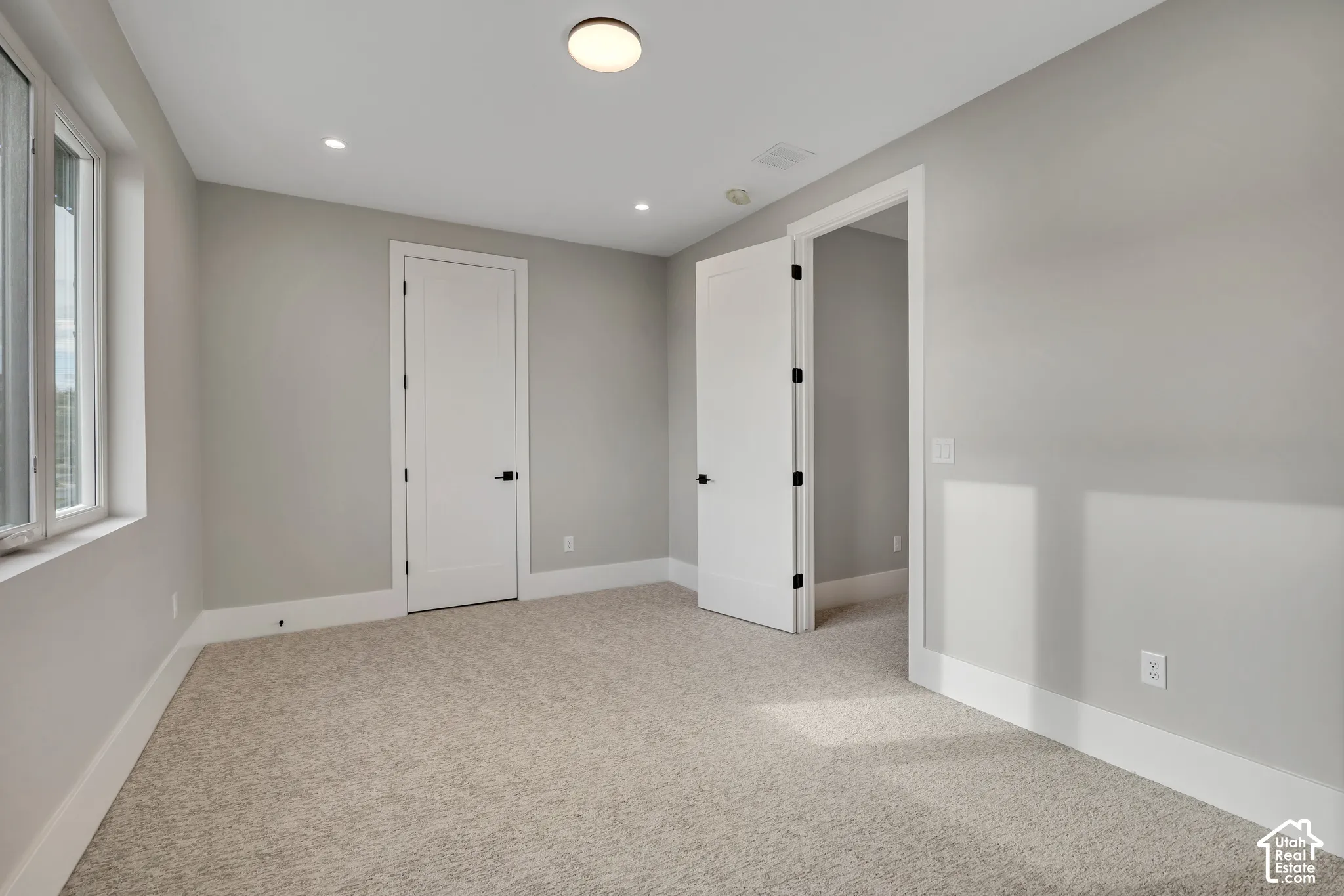 Neutral carpet flooring, light gray wall paint, recessed lighting, white trim work, and modern flat panel doors
