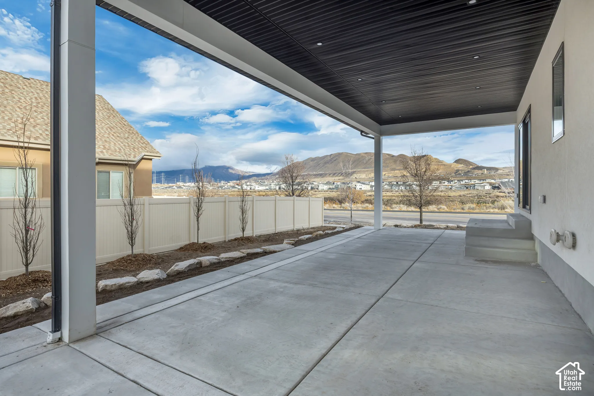 Covered patio with integrated lighting, concrete flooring, exterior stucco finish, and a mountain backdrop