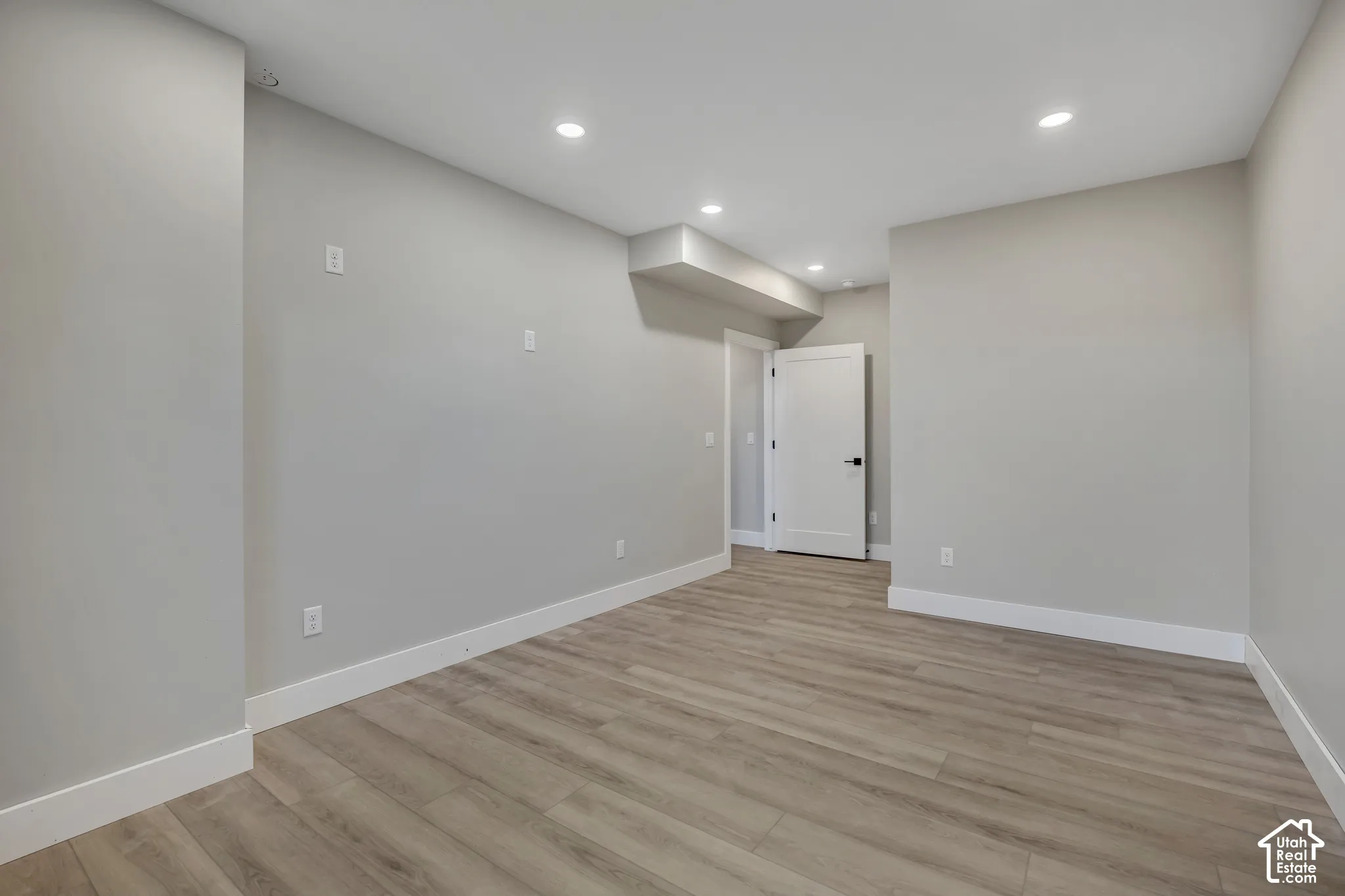 Recessed lighting illuminates the neutral wall tones and wood-finish flooring