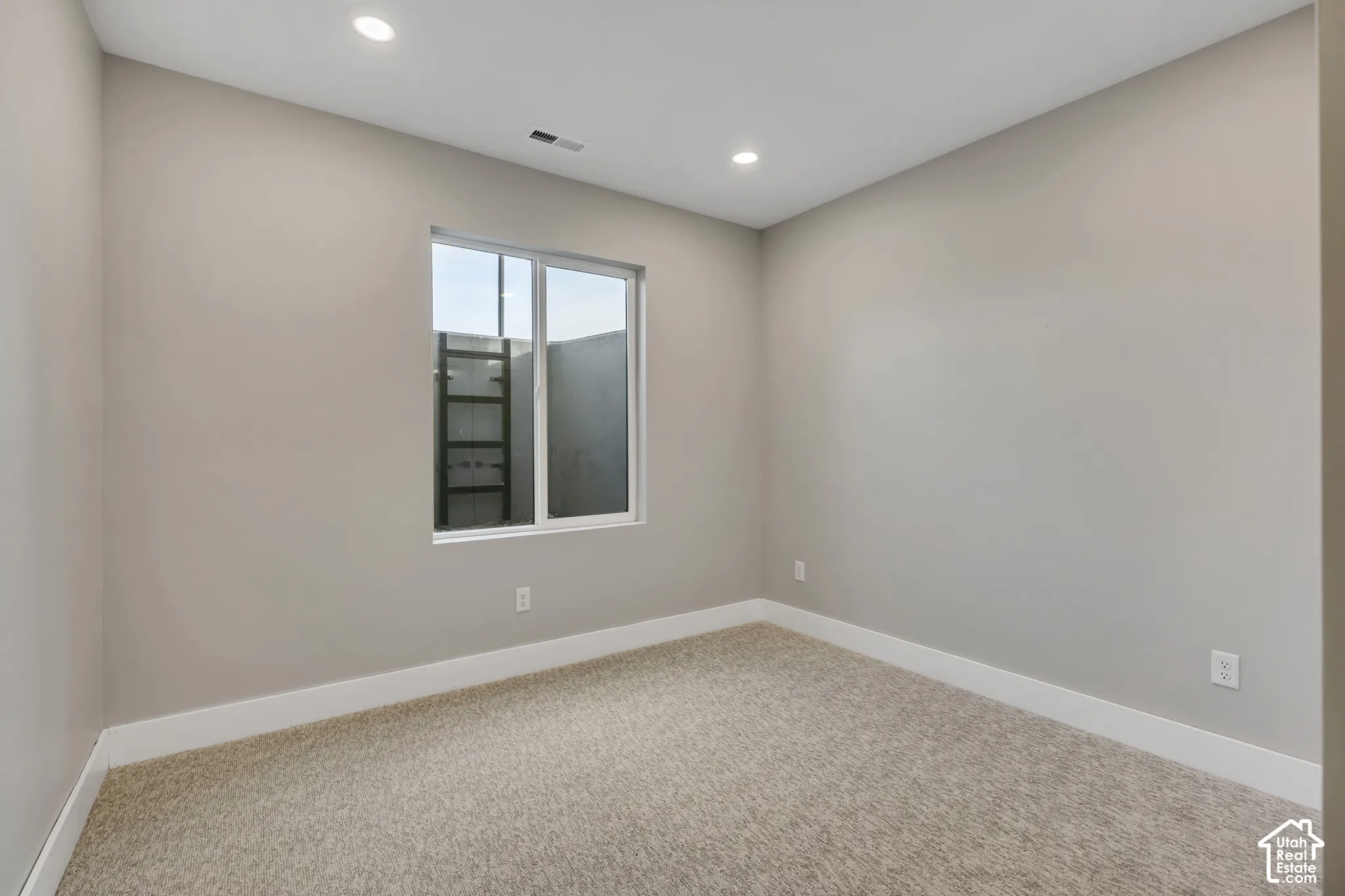 Neutral wall paint, recessed lighting, white window trim, and carpet flooring