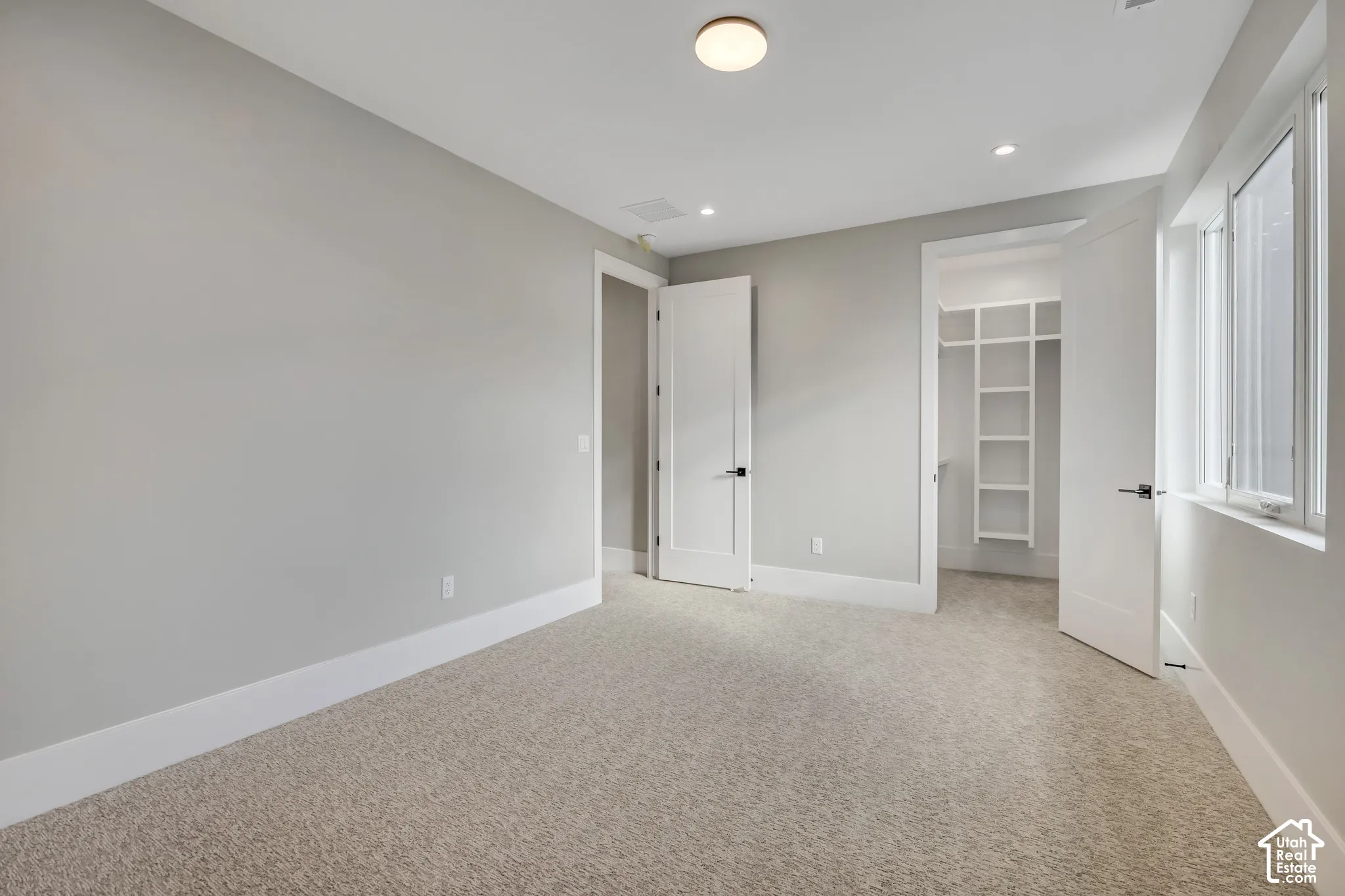 Recessed lighting, flush mount lighting, plush carpeting, built-in closet shelving, and a large window with white trim