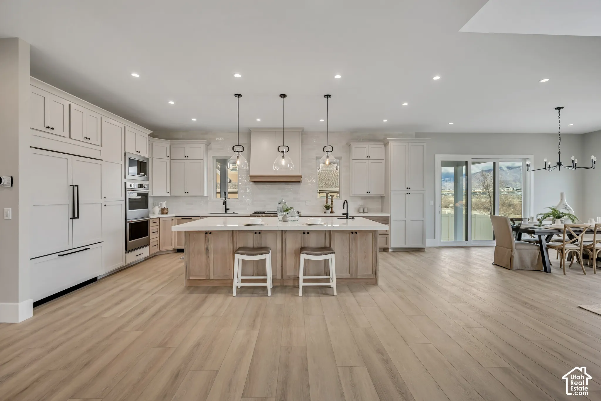 Gourmet kitchen with wood-finish flooring, two-tone cabinetry, a large center island, and stainless steel appliances