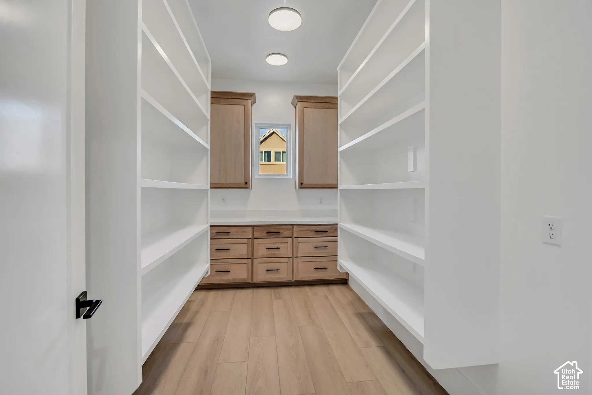 Extensive built-in shelving, wood-finish flooring, recessed lighting, base cabinetry with drawer storage, and upper cabinetry