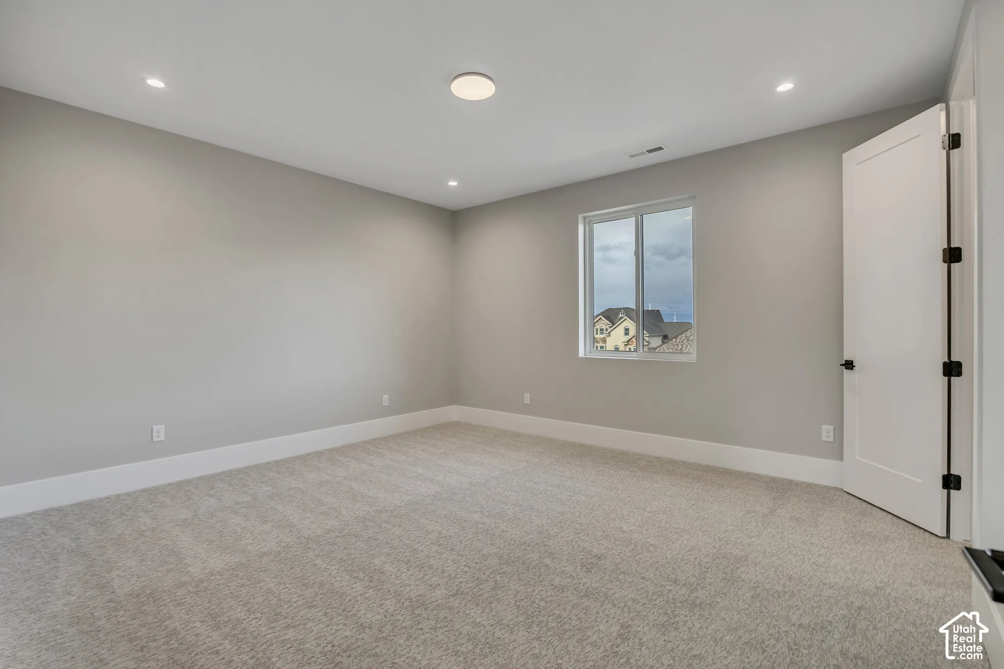 Recessed lighting, flush-mount ceiling fixture, light gray carpeting, white trim, and a white interior door with black hardware