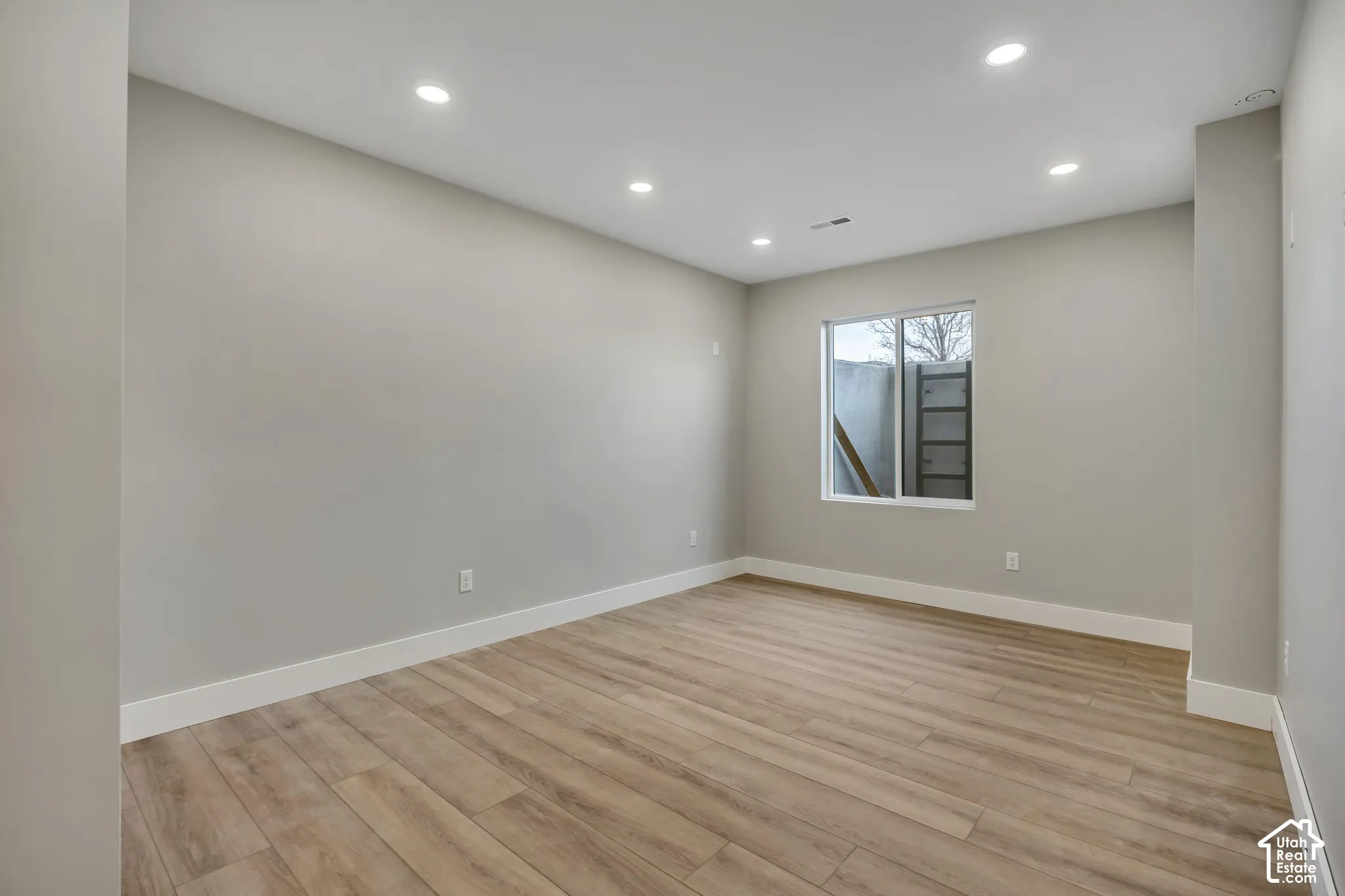 Recessed lighting, wood-finish flooring, white trim, and a window with a white frame