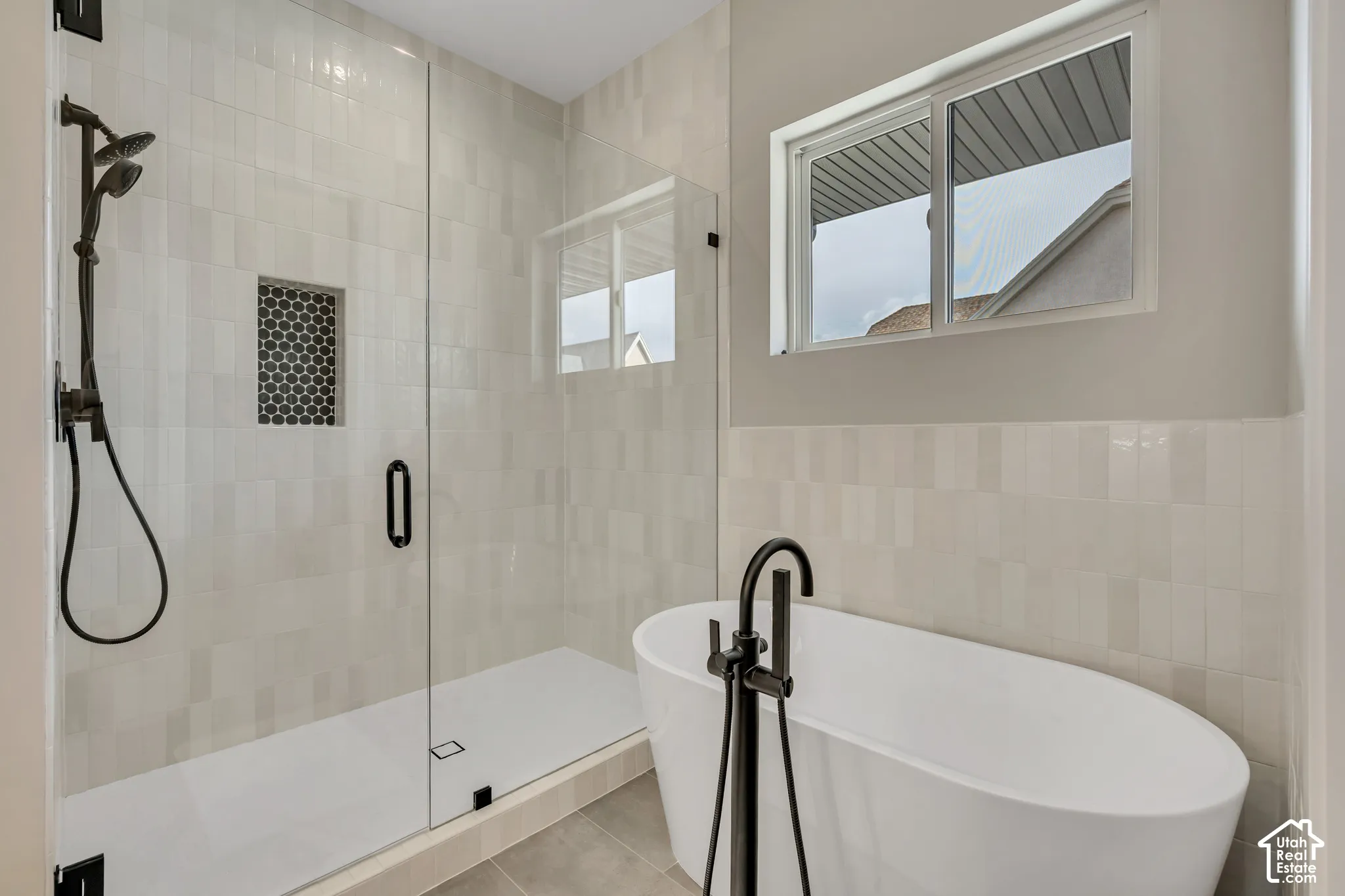 Walk-in shower with a glass enclosure, black hex-tile shower niche, and matte black fixtures