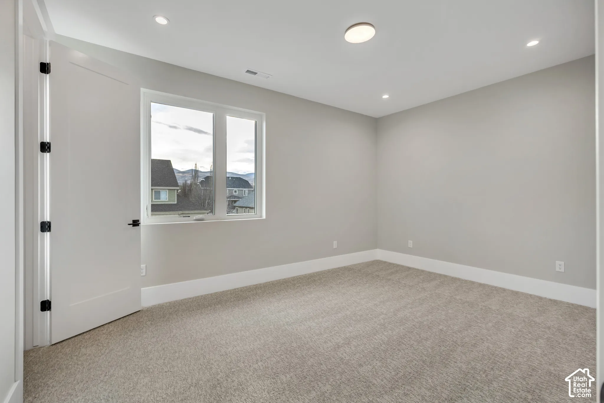 Neutral tone paint, recessed lighting, white trim, carpet flooring, and a large window