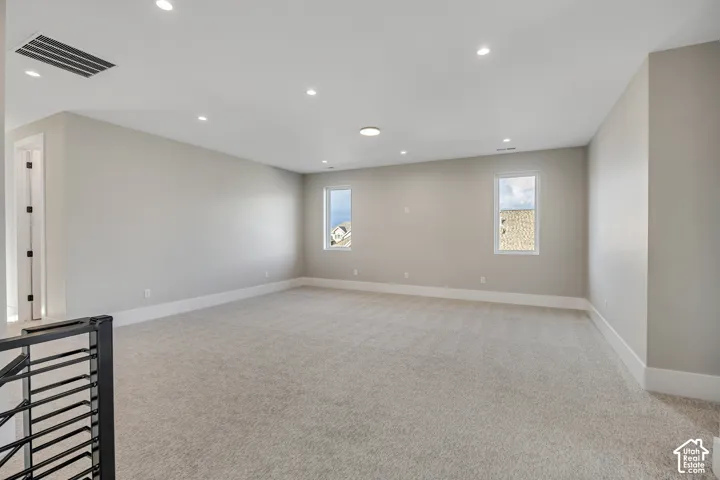 Spacious room with light neutral carpet flooring, recessed ceiling lighting, and multiple windows