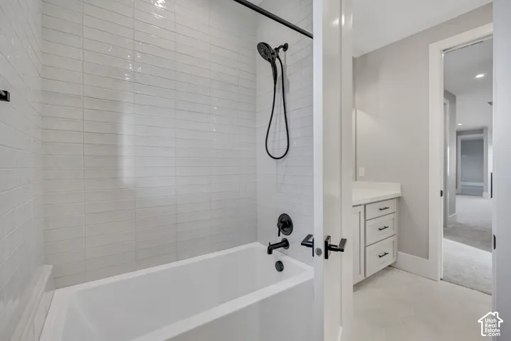 Shower-over-tub with matte black fixtures, white subway tile surround, and light-colored flooring